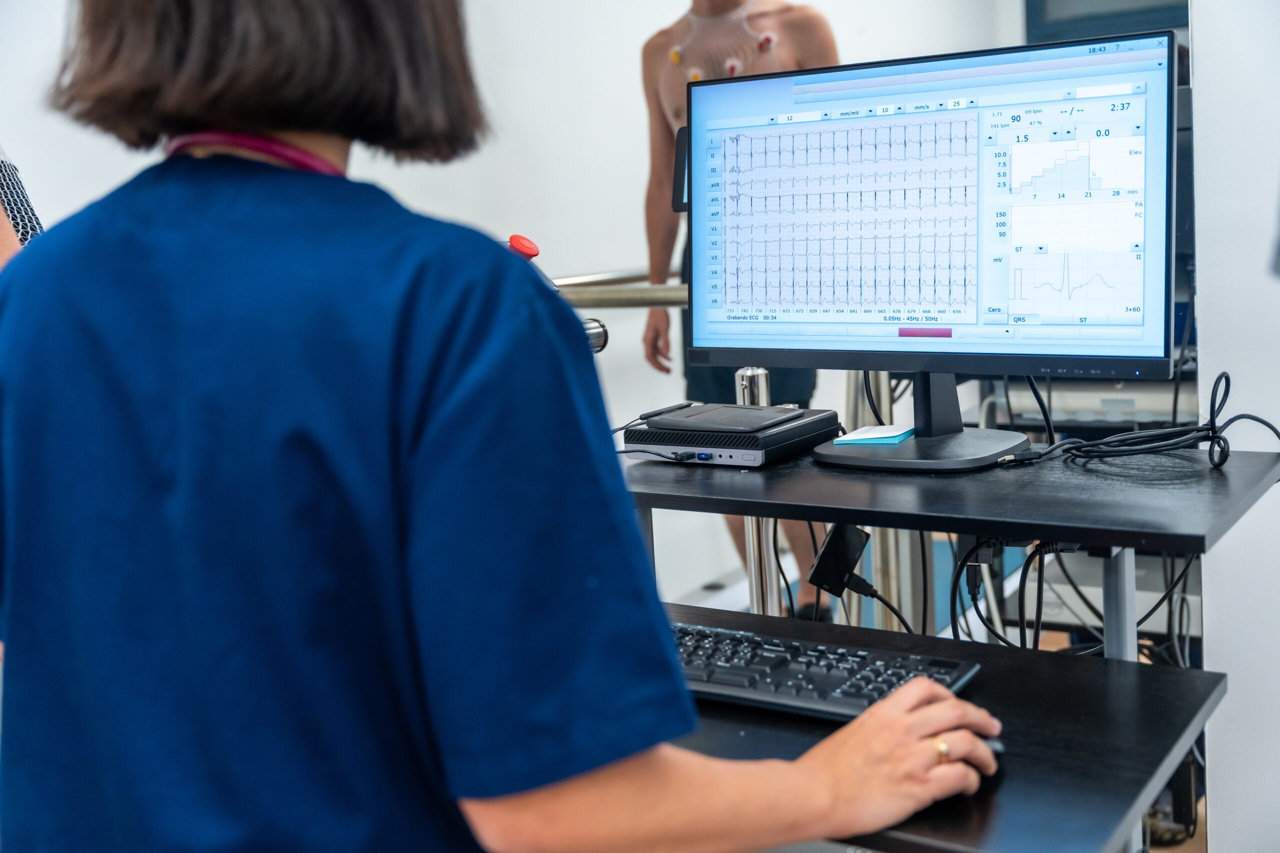 Doctor reviewing ECG results on computer during patient stress test.