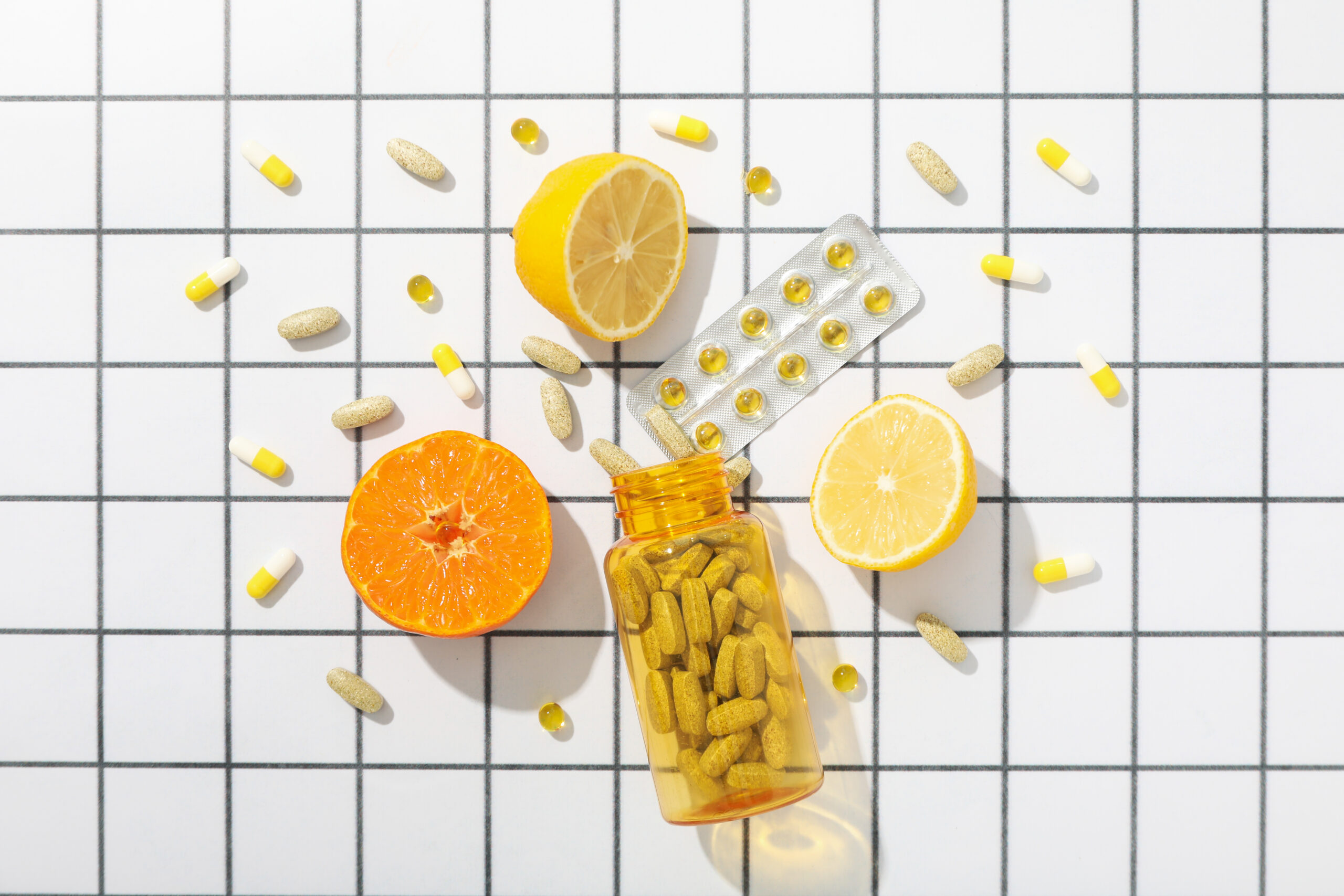 Assortment of vitamin pills, tablets, and citrus fruits.
