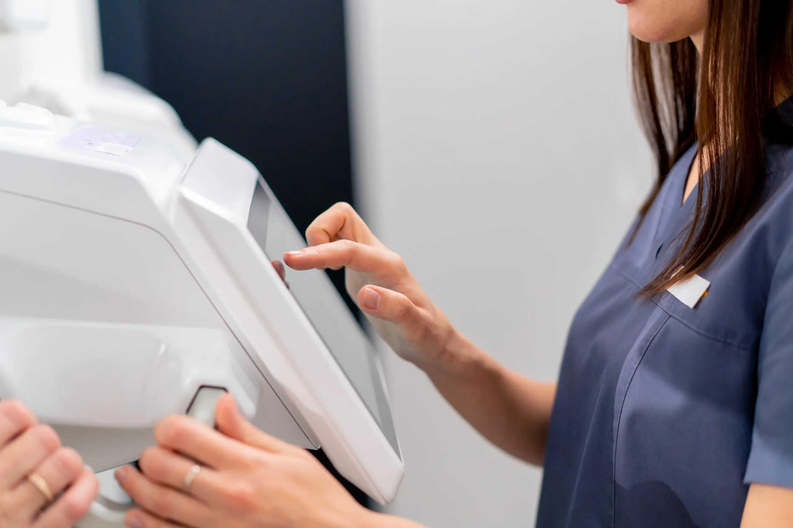 Close-up of a technician operating a medical device's touchscreen.
