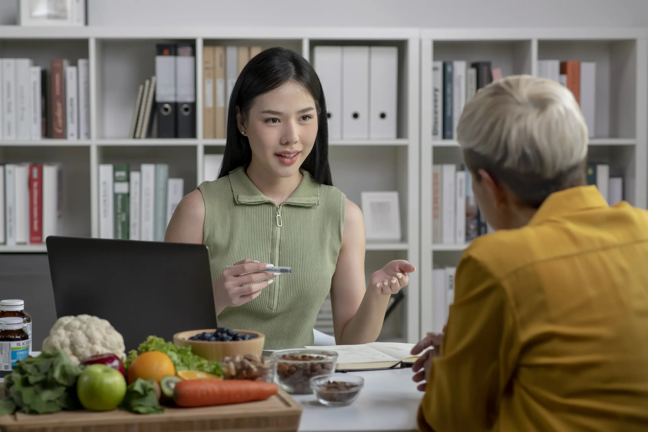 Nutritionist consulting client about anti-aging hormone package, healthy food on table.