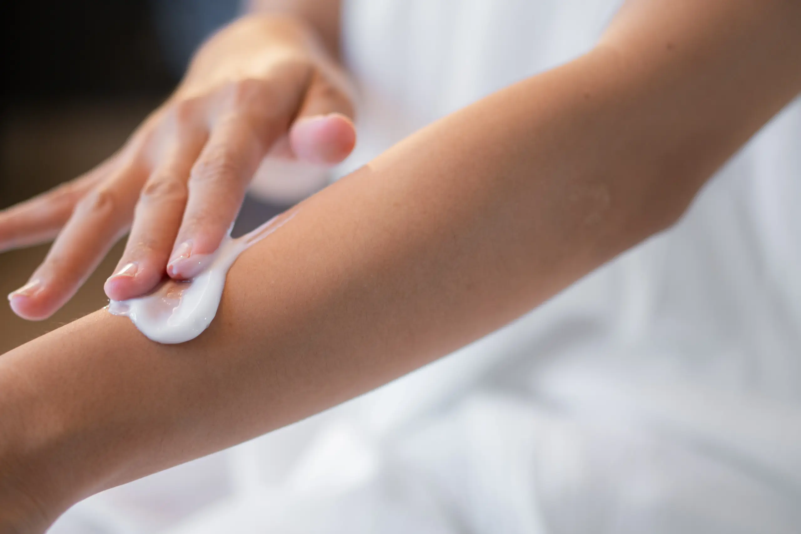 Person applying lotion to their arm.