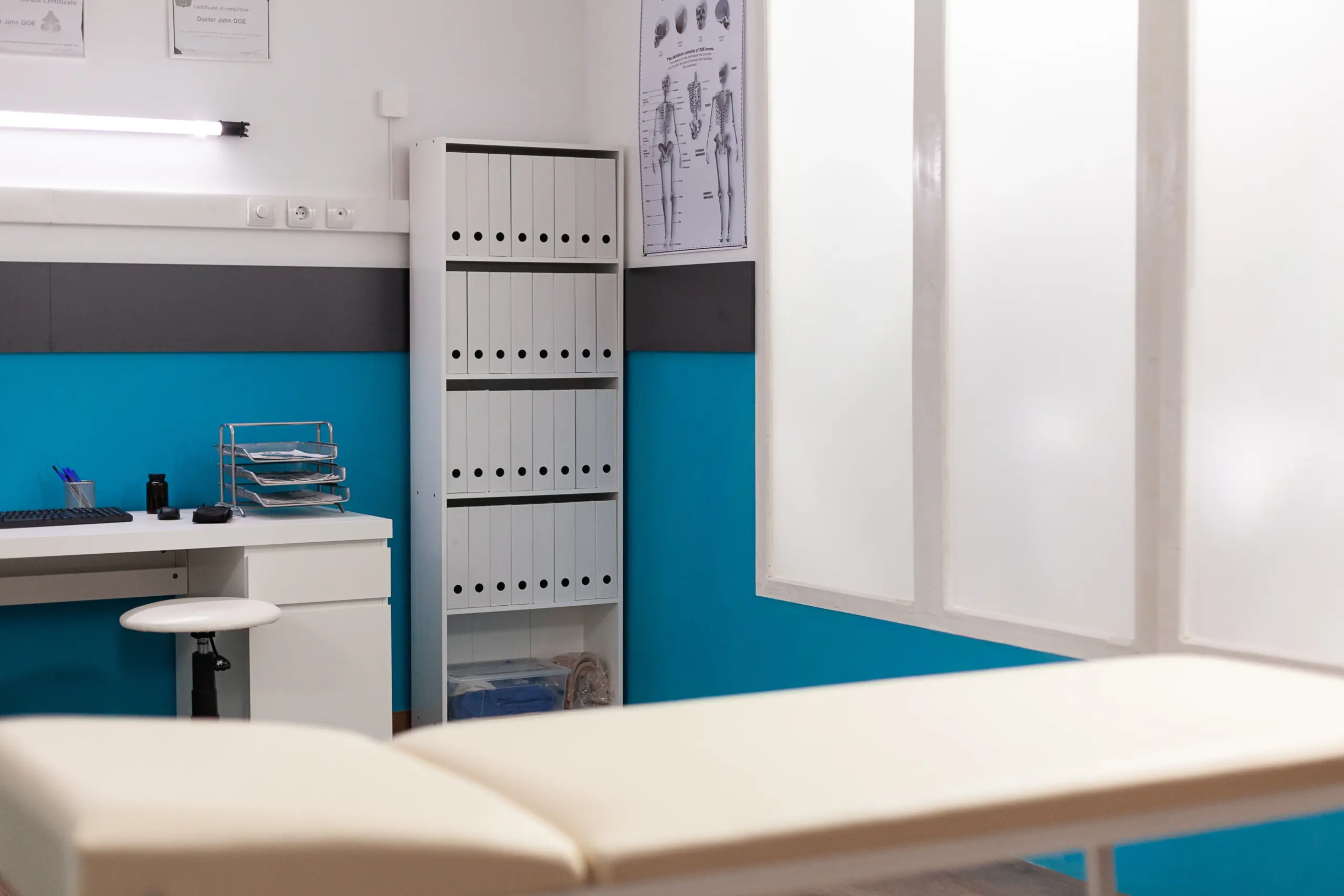 Clean, modern medical office with examination table and file cabinet.