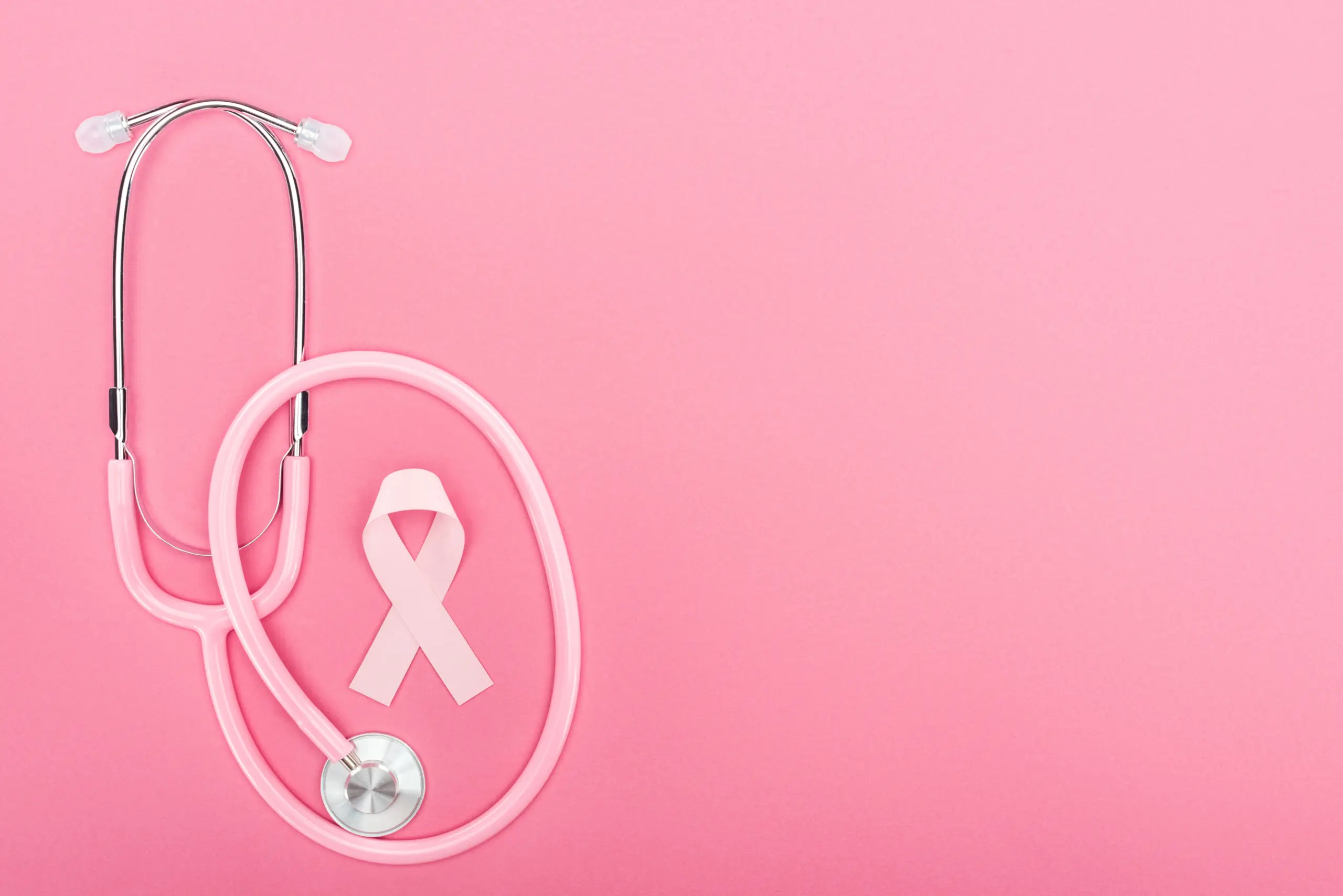 Pink stethoscope and ribbon on pink background. Breast cancer awareness.
