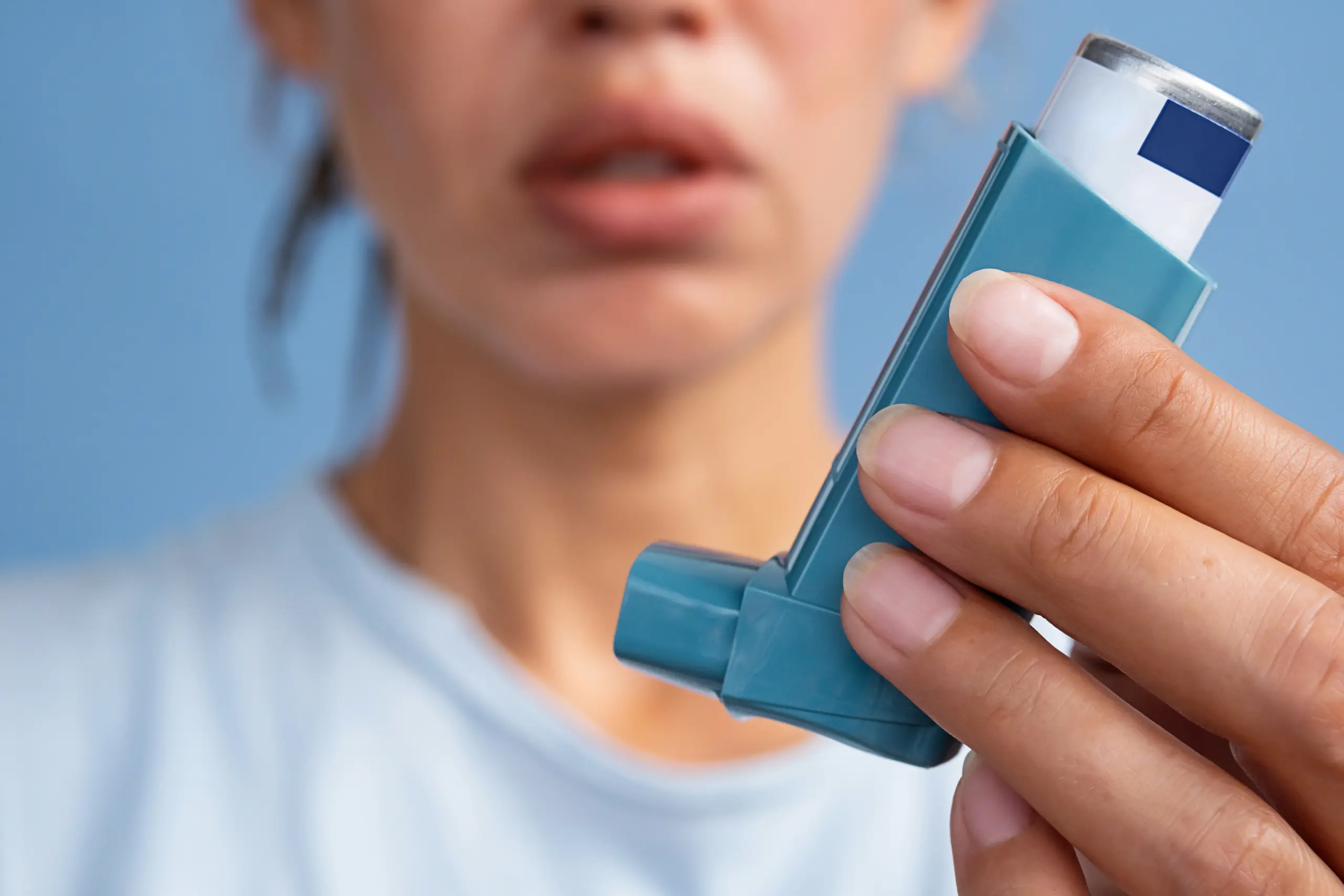 Close-up of a person's hand holding an inhaler.