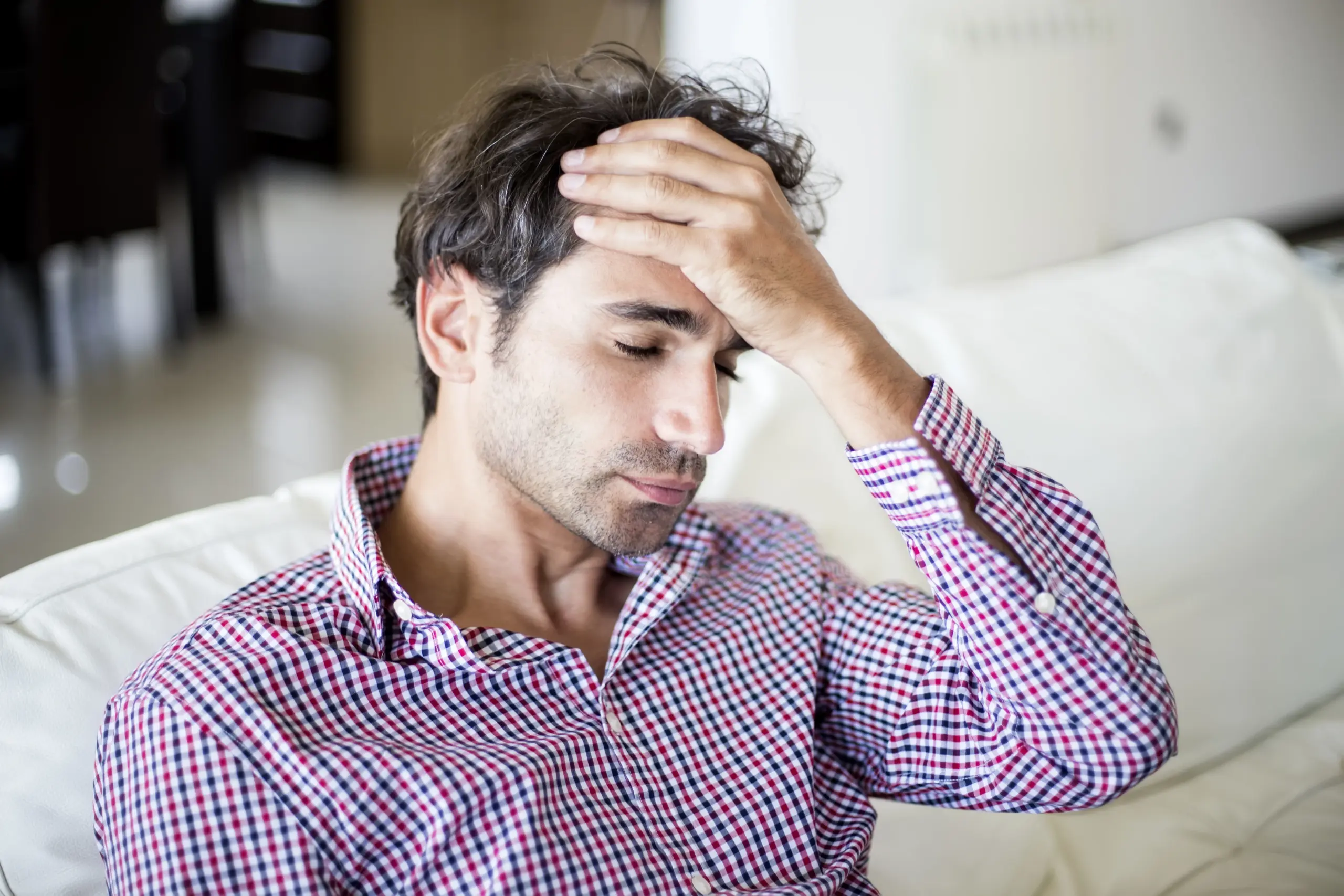 Man holding his head, appearing stressed or experiencing a headache.