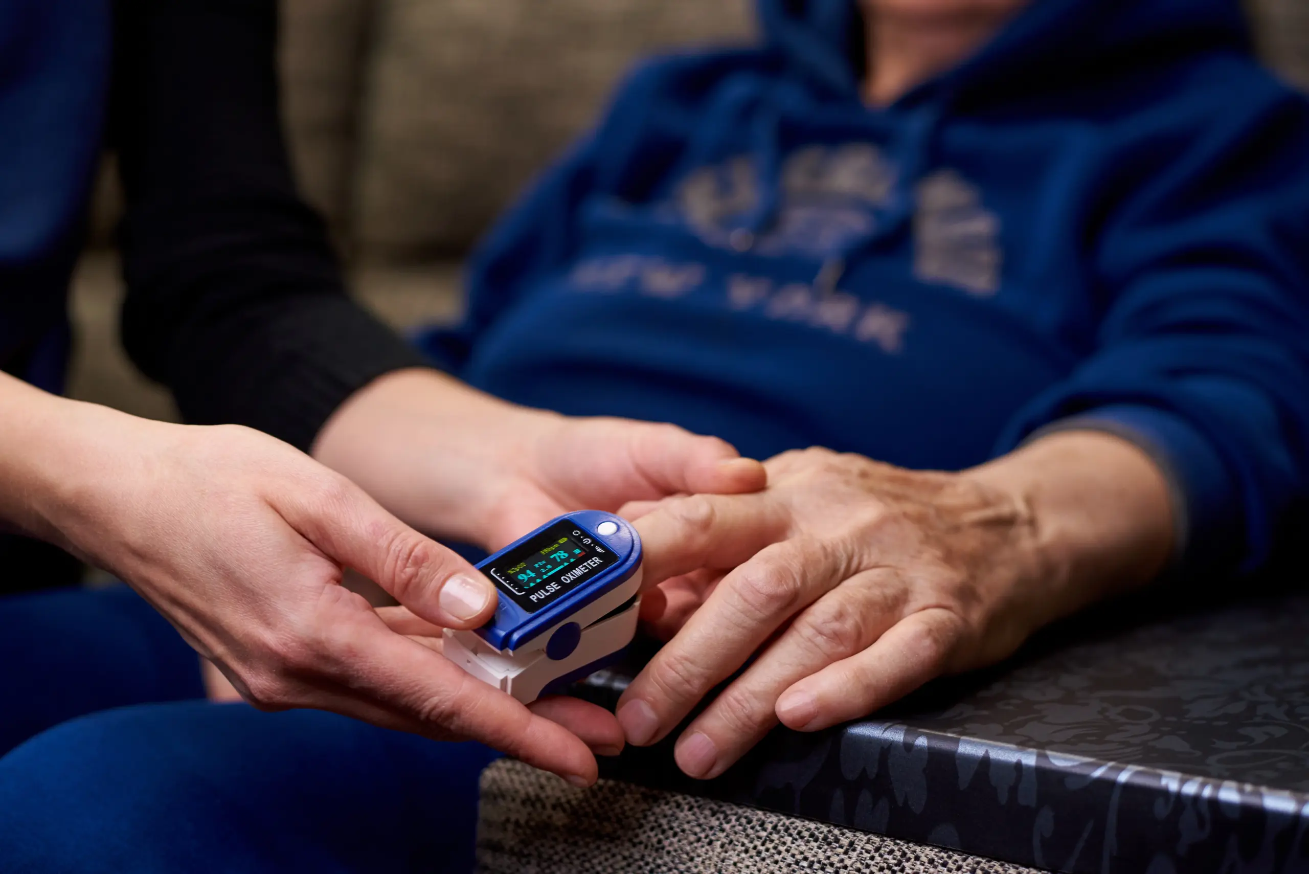 Nurse using pulse oximeter for health screening, displaying SpO2 94% and pulse 78 bpm.