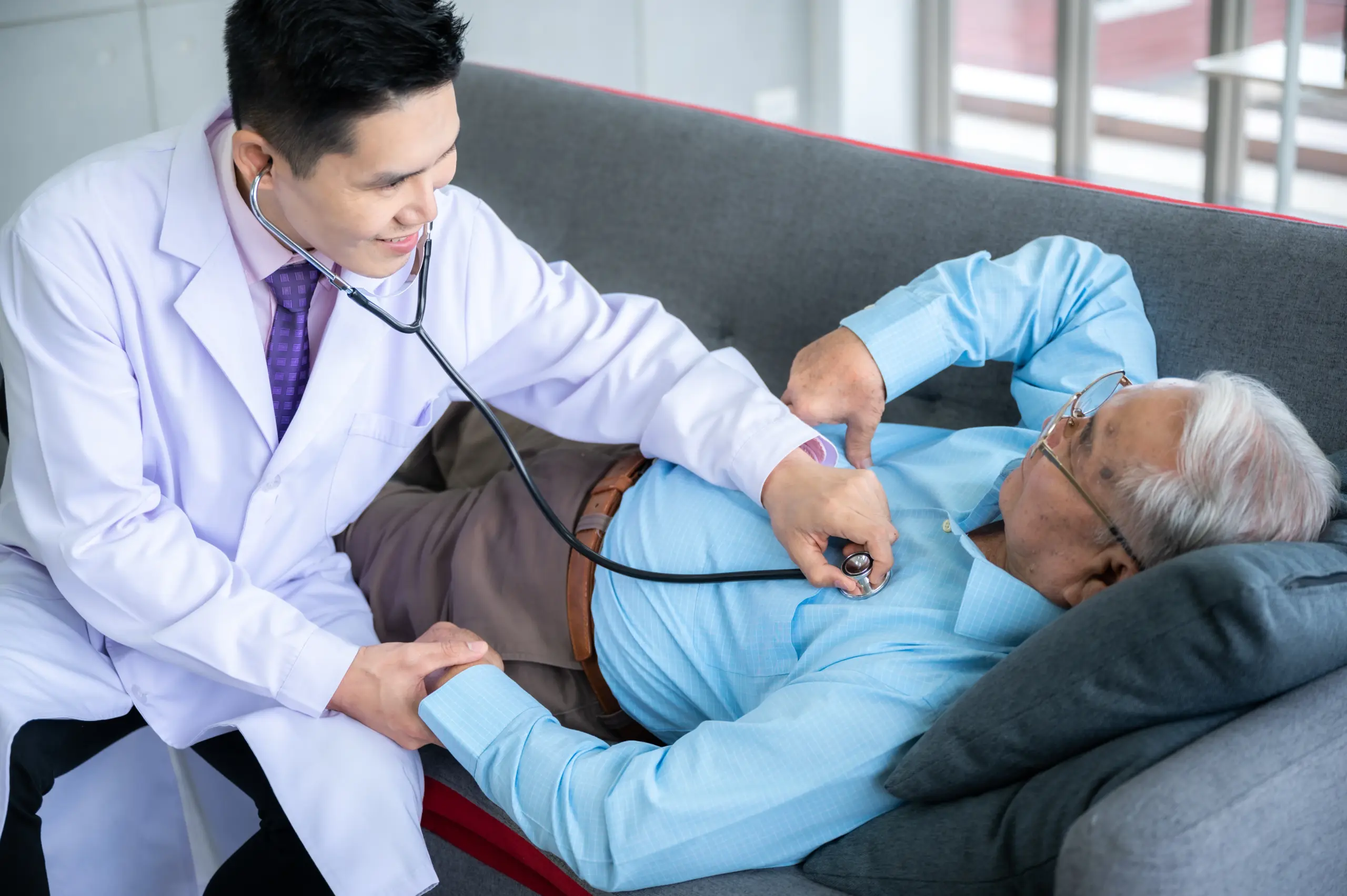 Doctor using a stethoscope to examine a senior patient's chest during a geriatric health screening.