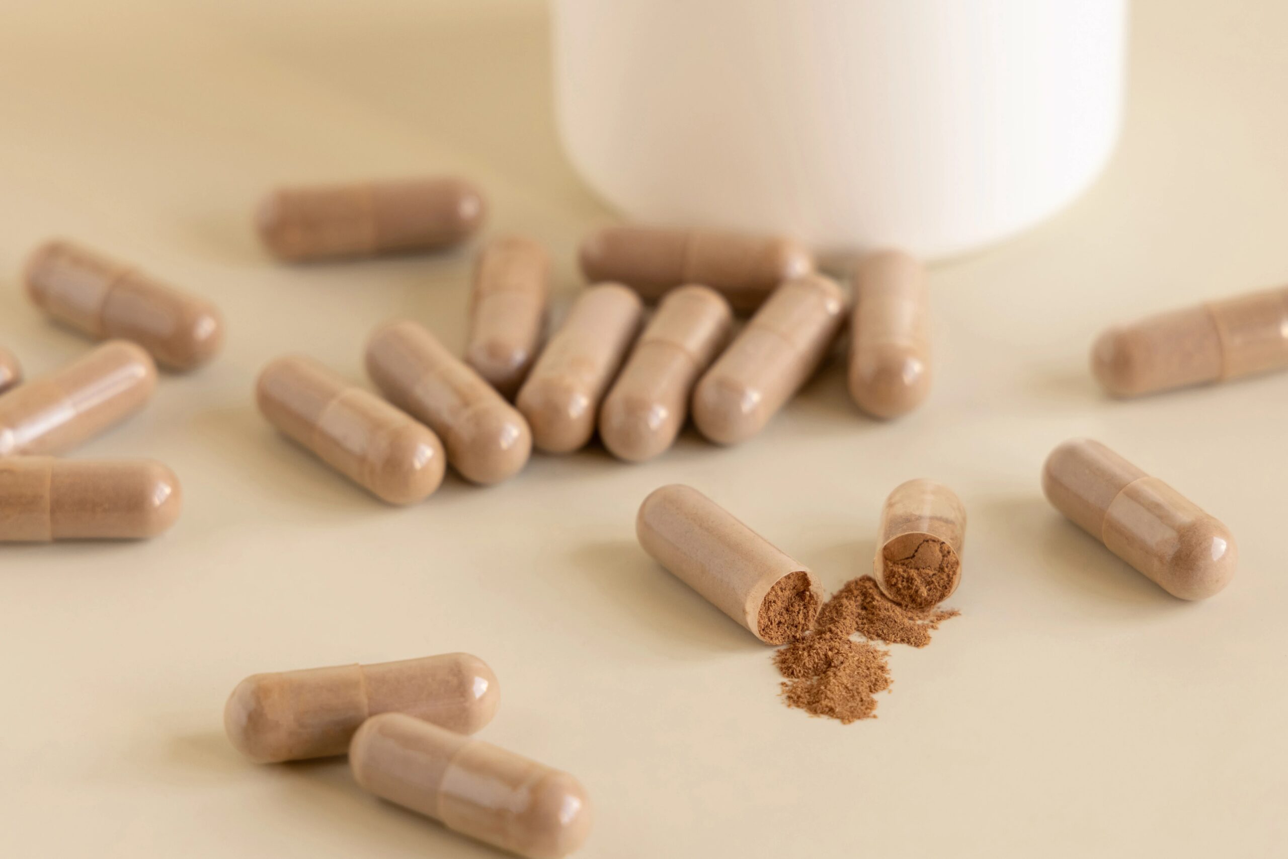 Brown capsules spilled on a beige surface, one broken open revealing its powder contents. Heavy metal toxicity test.