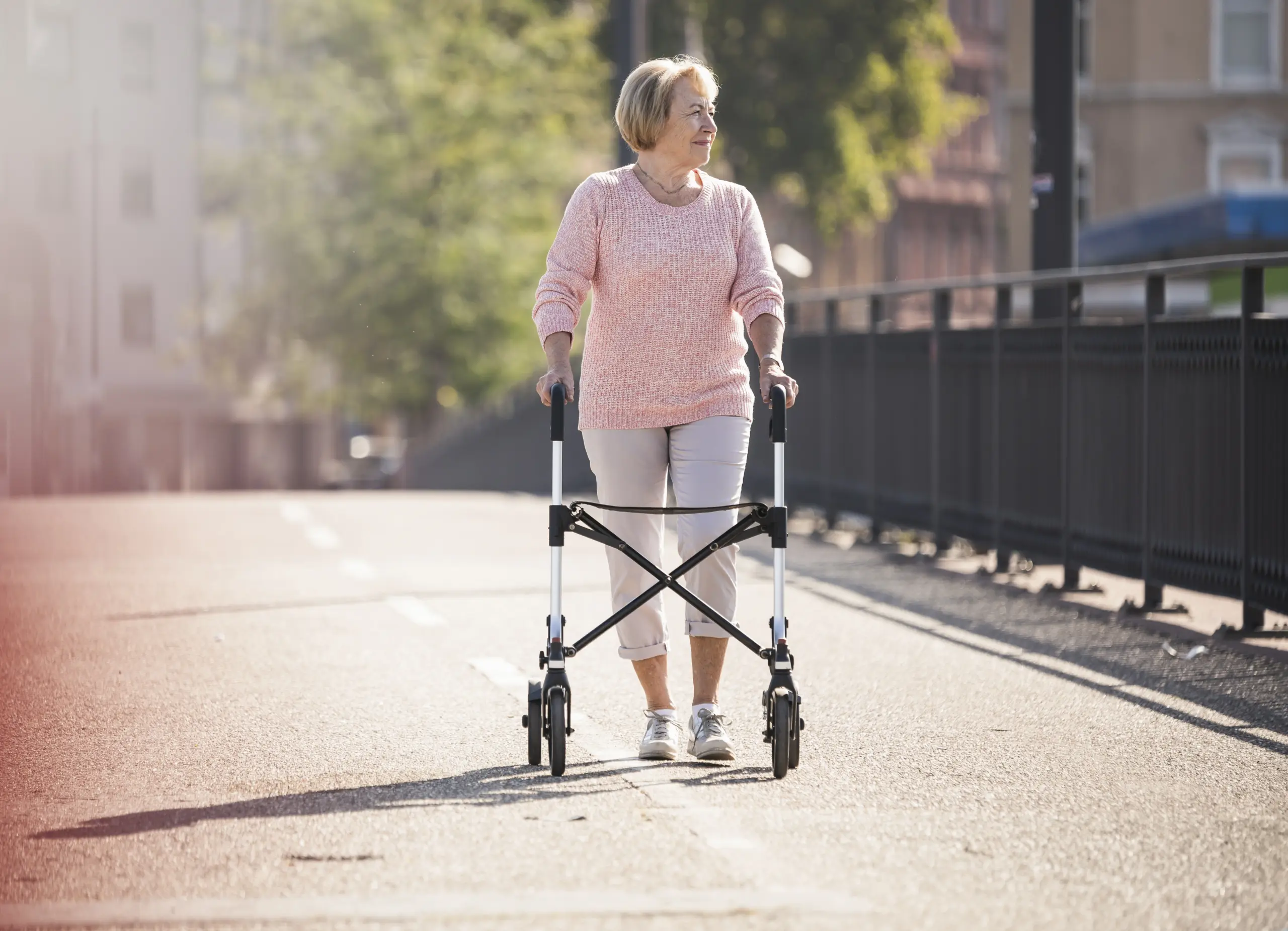 Senior woman walking with a rolling walker outdoors.