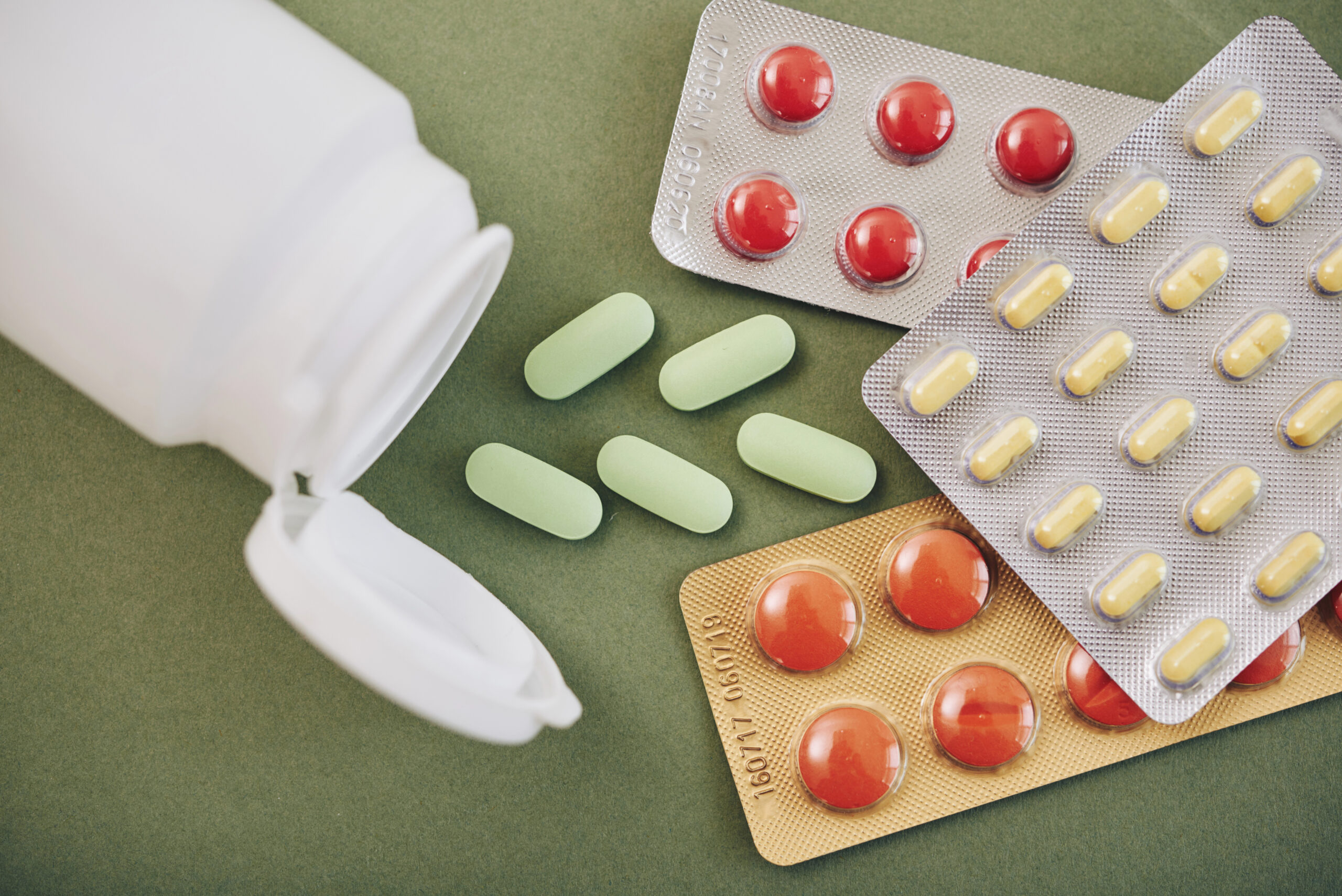 Various blister packs and tablets on a green surface