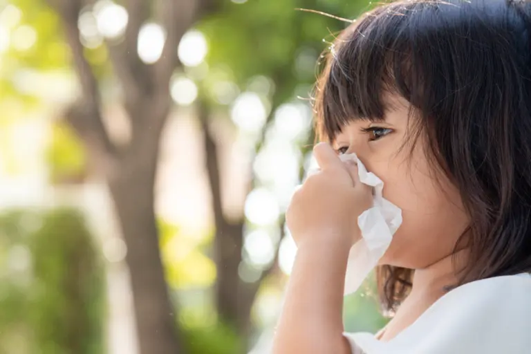 Young Asian girl sneezing, showing allergy symptoms in children