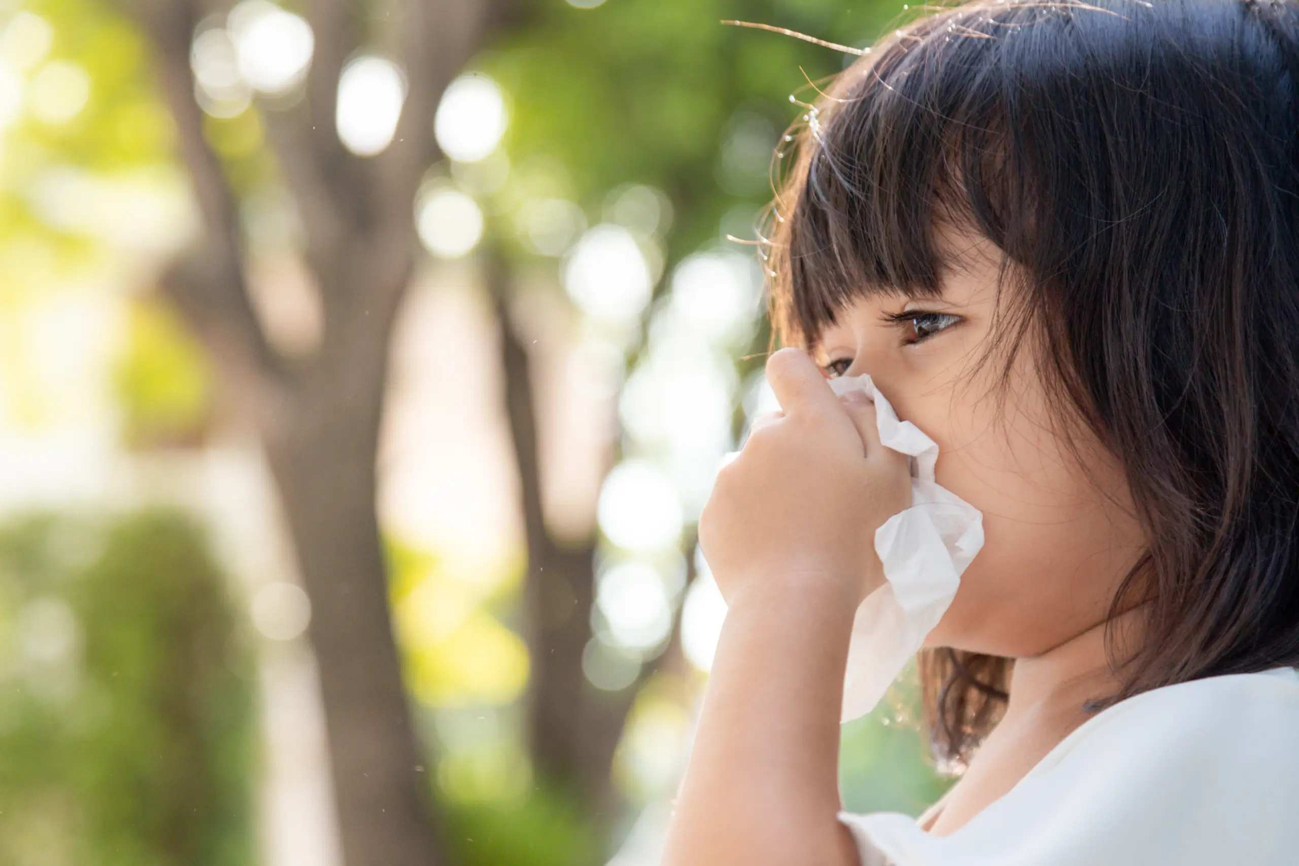Young Asian girl sneezing, showing allergy symptoms in children
