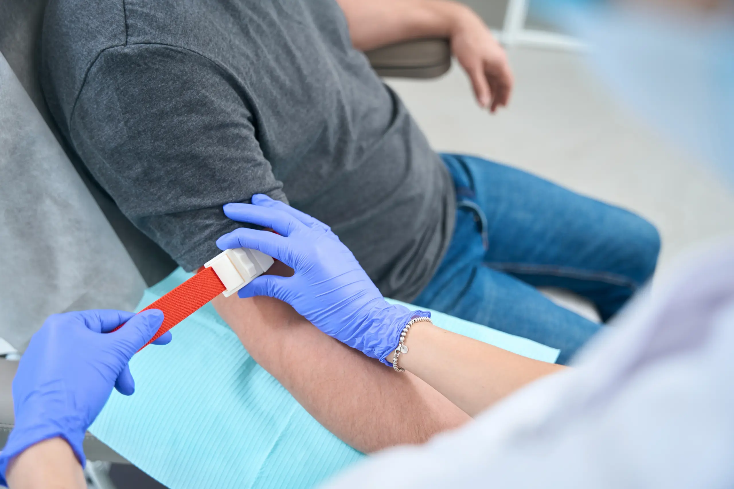 Nurse applying a tourniquet before a blood draw at a medical check-up