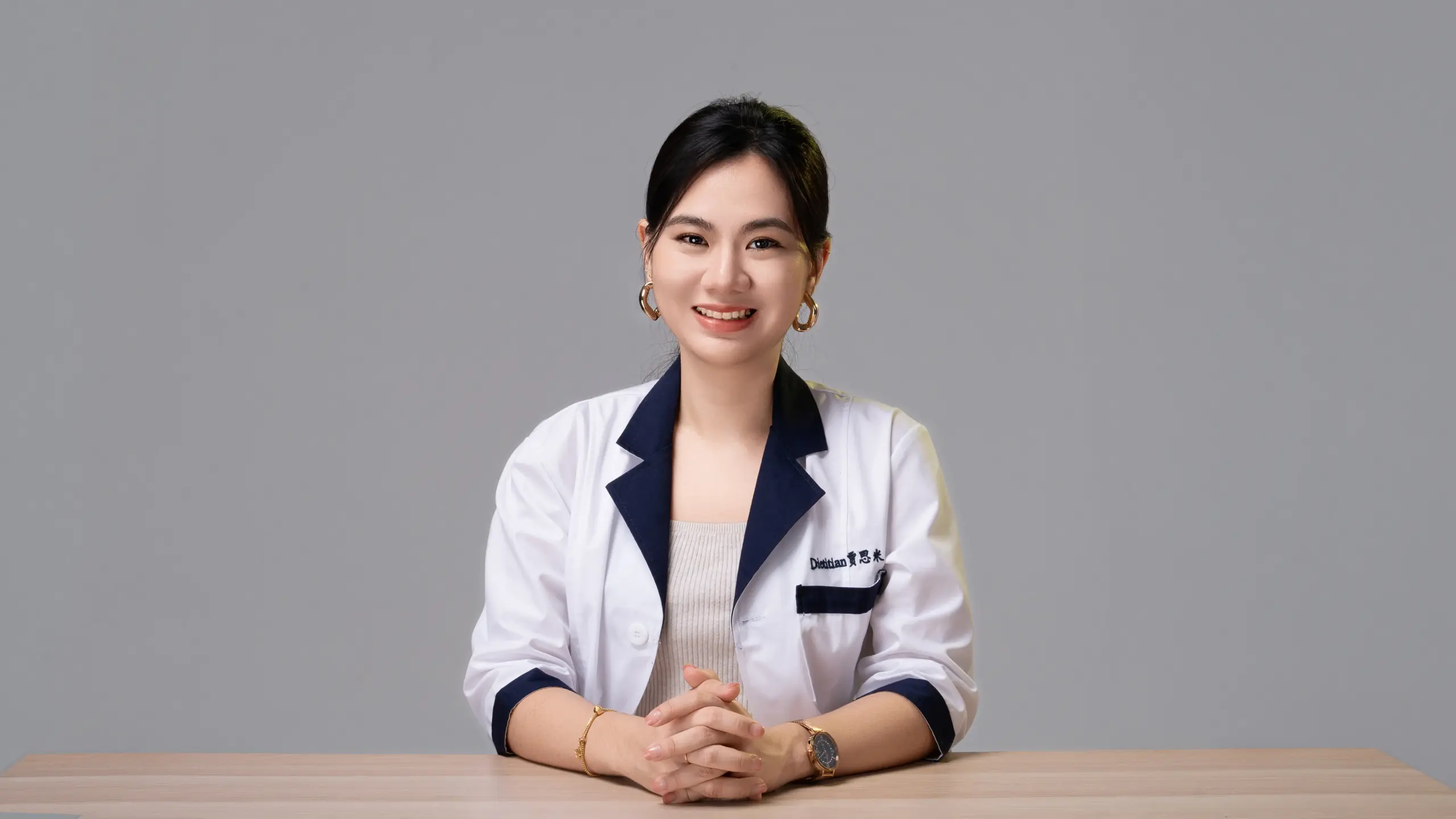 Smiling person in a lab coat at desk